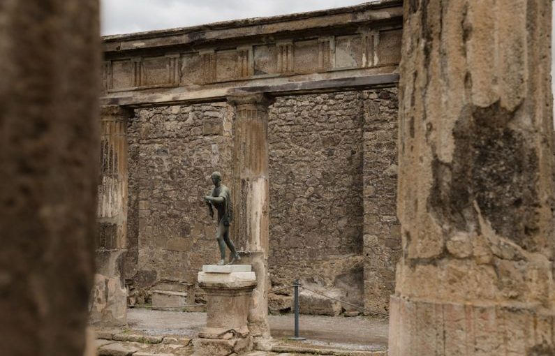Pompeii Ruins - a statue of a man is in between two pillars