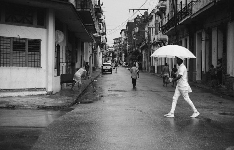 Havana Streets - man holding umbrella walking on gray road